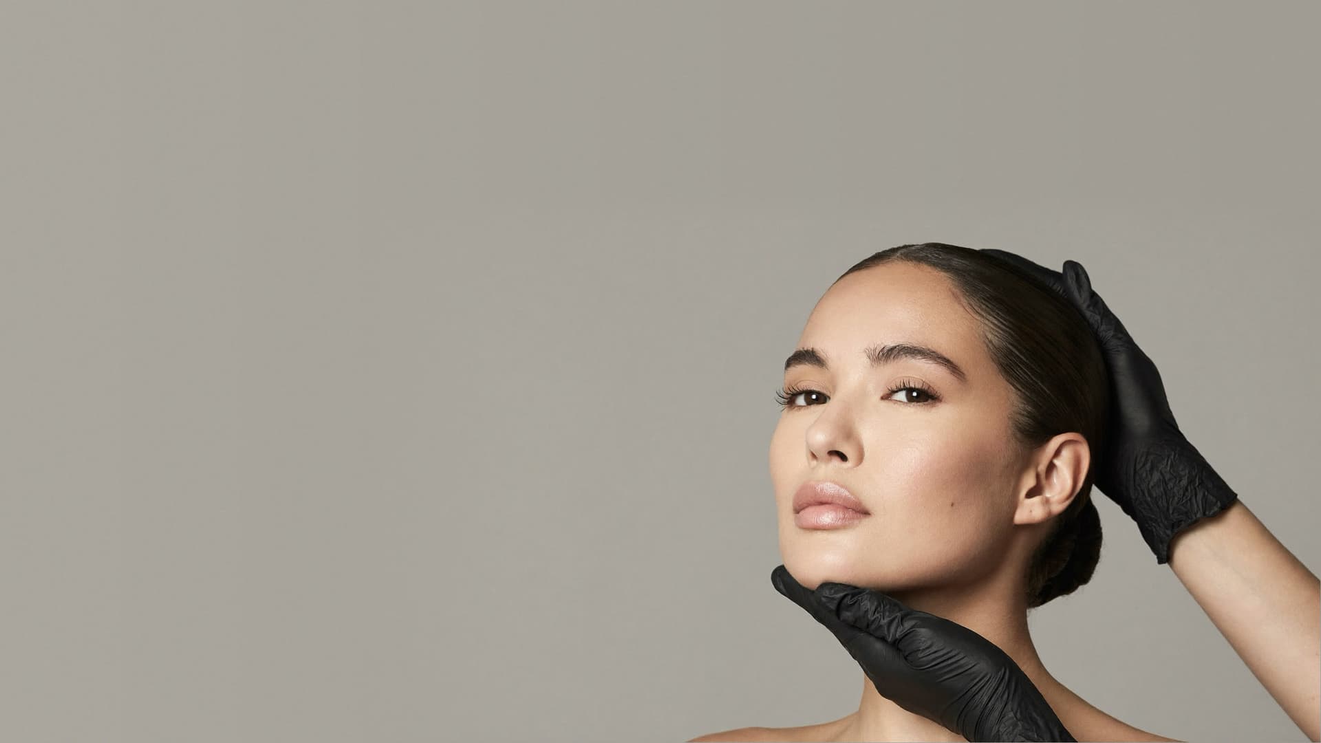 Illustrative image: a specialist's gloved hands framing a woman's face